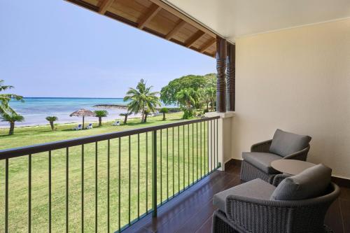 a balcony with chairs and a view of the beach at Sheraton Samoa Beach Resort in Mulifanua