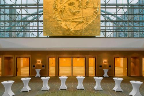a room with white chairs and a painting on the wall at Sheraton Brussels Airport Hotel in Zaventem