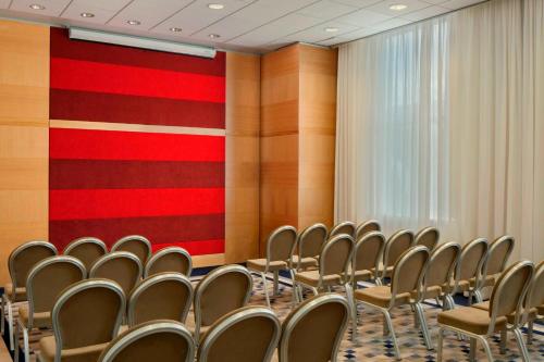 a room with rows of chairs and a red wall at Sheraton Brussels Airport Hotel in Zaventem