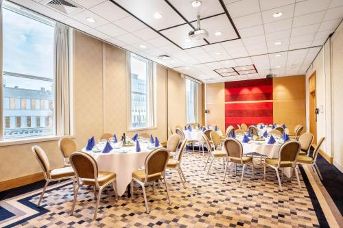 a conference room with tables and chairs and windows at Sheraton Brussels Airport Hotel in Zaventem