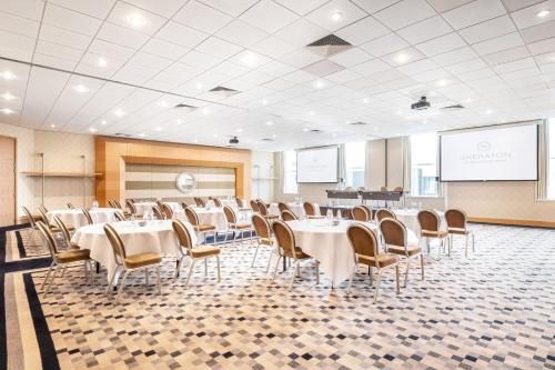 a conference room with tables and chairs and a projection screen at Sheraton Brussels Airport Hotel in Zaventem