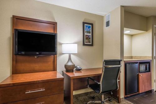 a hotel room with a desk with a television and a chair at Comfort Inn & Suites Dayton North in Dayton
