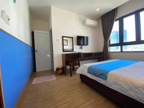 a bedroom with a bed and a desk and a window at Hotel Hoàng Hưng Quy Nhơn in Quy Nhon