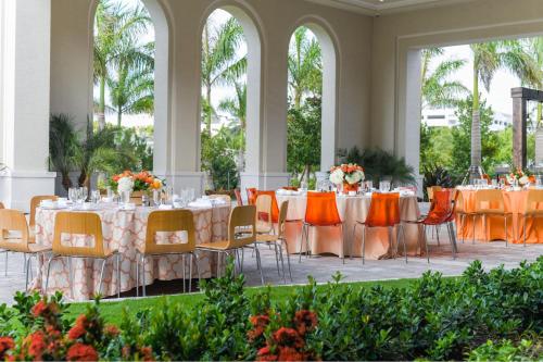 a banquet hall with tables and chairs with orange chairs at JW Marriott Miami Turnberry Resort & Spa in Aventura