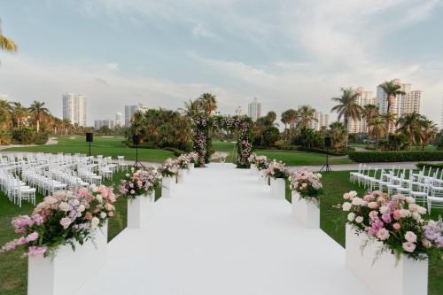 a wedding aisle with white chairs and pink flowers at JW Marriott Miami Turnberry Resort & Spa in Aventura