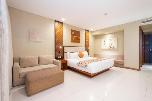 a bedroom with a bed and a chair and a couch at VOUK Hotel and Suites Nusa Dua Bali in Nusa Dua