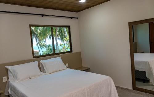 a bedroom with a bed and a window and a mirror at Aconchego Dona Quita in São Miguel dos Milagres