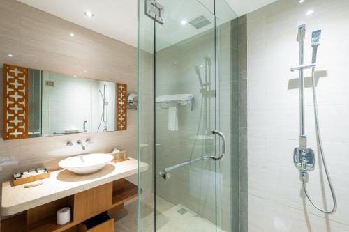 a bathroom with a sink and a glass shower at VOUK Hotel and Suites Nusa Dua Bali in Nusa Dua