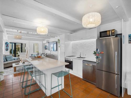 a kitchen with a refrigerator and a table and chairs at Poolside Waterfront - Orewa Oceanside Villa in Orewa