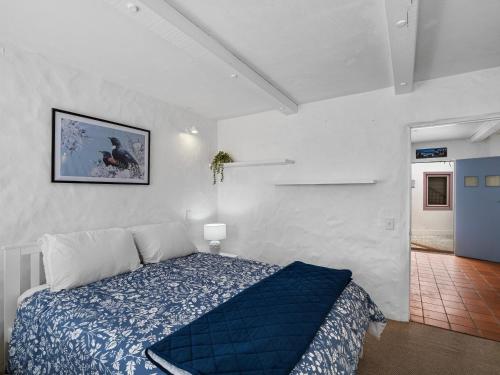 a bedroom with a blue bed in a white room at Poolside Waterfront - Orewa Oceanside Villa in Orewa