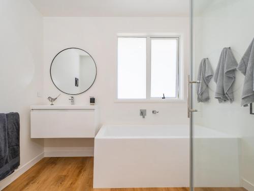 a white bathroom with a sink and a mirror at Greenhills Charmer - Coromandel Town Holiday Home in Coromandel Town