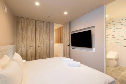 a bedroom with a large white bed and a television at Olaf House in Niseko