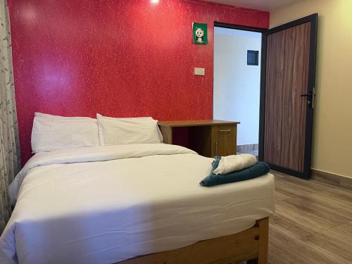 a bedroom with a large bed with a red wall at The North Face Inn's Homestay in Pokhara