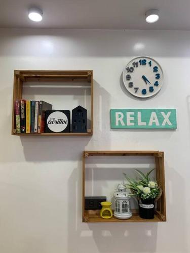 a wall with two shelves with a clock and a sign at Kidapawan Staycation 1 in Manongol