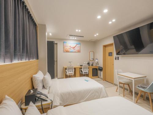 Una habitación de hotel con dos camas y un televisor. en Hotel Leo Changwon Central Branch, en Changwon