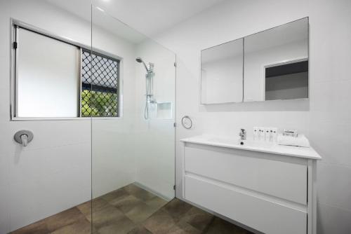 a white bathroom with a sink and a shower at Allamanda Sands in Peregian Beach