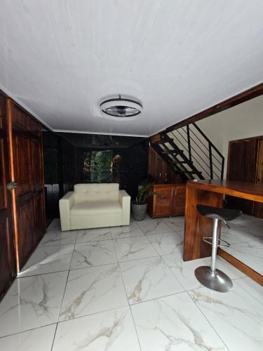 a living room with a white couch and a stool at Happy Paradise Lodge in Nuevo Arenal