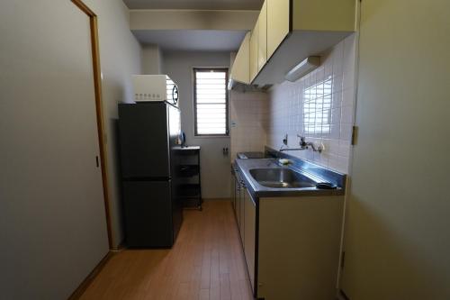 a small kitchen with a sink and a refrigerator at 浜ノ町瀬戸凪 in Takamatsu
