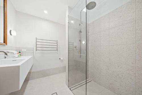 a white bathroom with a shower and a sink at Claytons 7 by Discover Stradbroke in Point Lookout