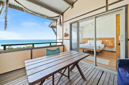 a room with a table and a bedroom with the ocean at Claytons 7 by Discover Stradbroke in Point Lookout