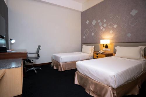 a hotel room with two beds and a desk at Paya Bunga Hotel Terengganu in Kuala Terengganu
