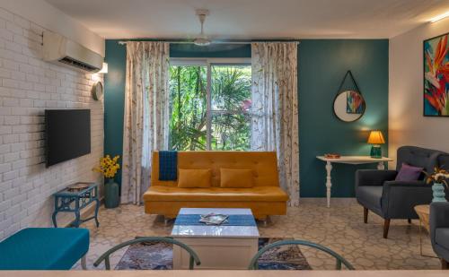 a living room with a couch and a tv at Santa Tera Homely 1&2bhk Apartments With Common Pool & Kitchen & Security & Wifi, Near to Candolim in Verem