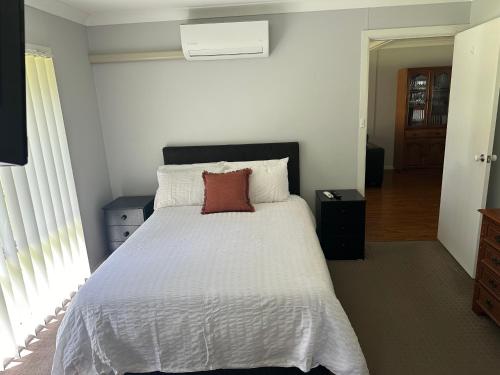 a bedroom with a white bed with a red pillow on it at Kollannoor Homestead in Mitchells Island