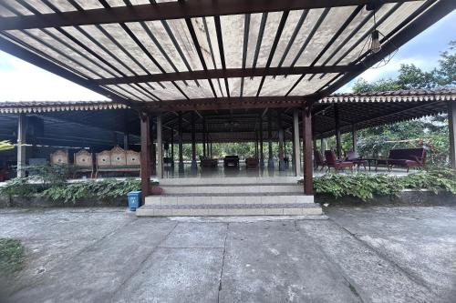 a pavilion with a wooden roof with stairs and chairs at Annet Homestay Yogyakarta in Balong