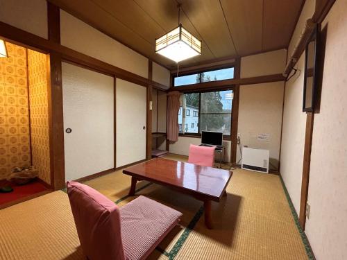 a living room with a table and two pink chairs at 池の平温泉 ロッジ コクハ in Myoko