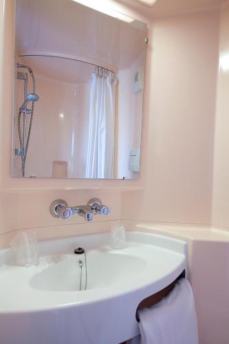 une salle de bain avec un lavabo blanc et un miroir dans l'établissement Première Classe Clermont-Ferrand Aubière, à Aubière