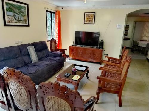 a living room with a couch and chairs and a tv at Baguio Transient Whole House in Baguio