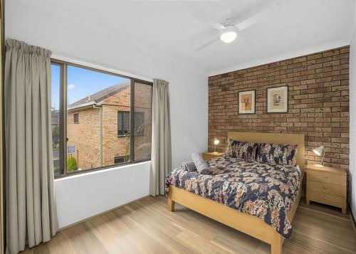 a bedroom with a bed and a large window at Banksia in Sawtell