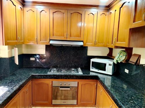 a kitchen with wooden cabinets and a stove and a microwave at Baguio Transient Whole House in Baguio
