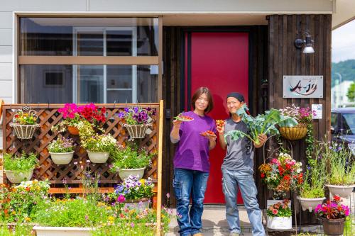 a man and a woman standing in front of a house with flowers at A-JA in Niki