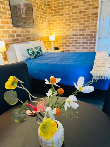 a room with a bed and a vase with flowers on a table at Town and Country Motor Inn in Tamworth