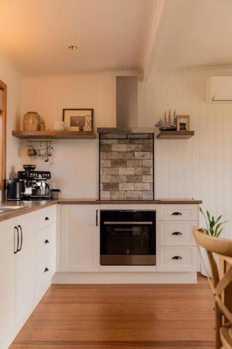 a kitchen with white cabinets and a fireplace at Bay Hideaway Stieglitz in Saint Helens Island