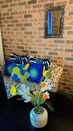 a couch with colorful pillows and a vase with flowers at Town and Country Motor Inn in Tamworth