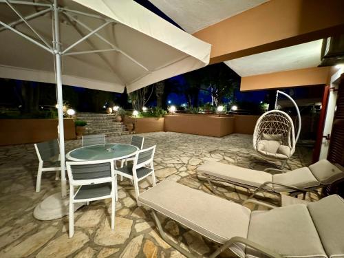 a patio with a table and chairs and an umbrella at Villa Pami in Almiros Beach
