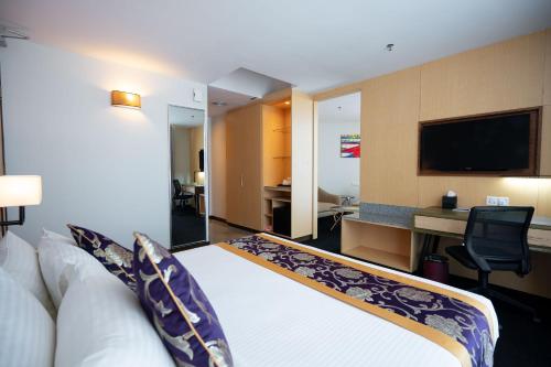 a hotel room with a bed and a desk and a television at Paya Bunga Hotel Terengganu in Kuala Terengganu