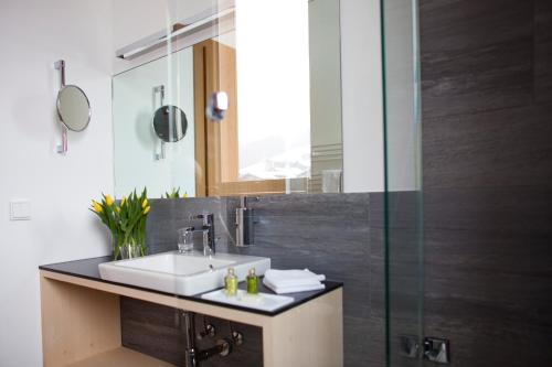 a bathroom with a sink and a glass shower at Alpina Lech - Geborgen in den Bergen in Lech am Arlberg