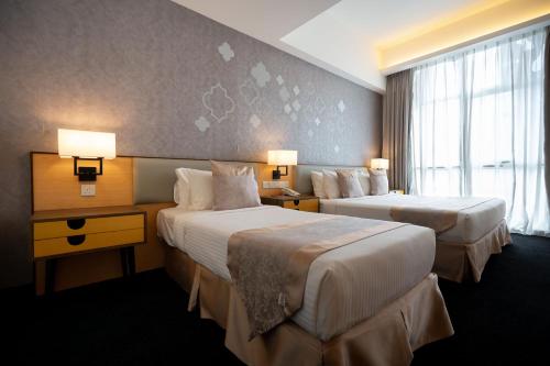 a hotel room with two beds and a window at Paya Bunga Hotel Terengganu in Kuala Terengganu