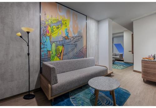 a living room with a couch and a painting on the wall at Harper Banjarmasin by ASTON in Banjarmasin