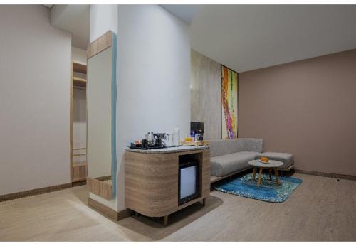 a living room with a couch and a tv at Harper Banjarmasin by ASTON in Banjarmasin