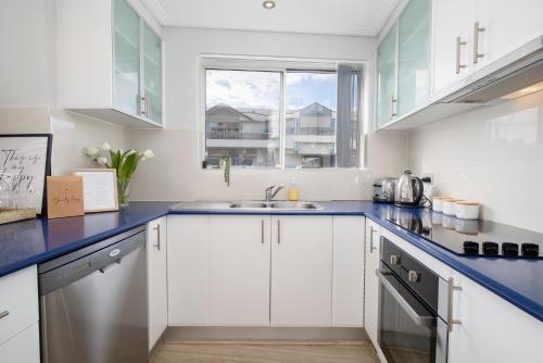 a kitchen with white cabinets and a blue counter top at Oceans at Terrigal a Beachfront Oasis in Terrigal