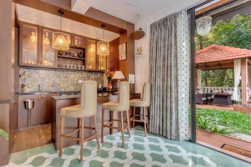 a kitchen with a bar with stools at Villa Stairway to Heaven by tisyastays in Candolim