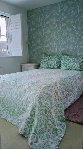 a bedroom with a bed with a green and white comforter at BIENVENUE in NEWHAVEN Luxury superking OR standard OR budget rooms in Newhaven