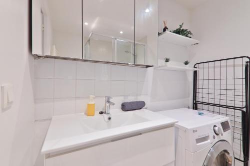 La salle de bains blanche est pourvue d'un lavabo et d'un lave-linge. dans l'établissement Charmant Appartement Quartier Tour Eiffel Free Netflix, à Paris