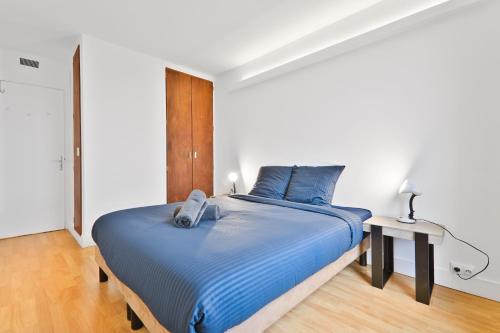 une chambre avec un grand lit avec des draps bleus dans l'établissement Charmant Appartement Quartier Tour Eiffel Free Netflix, à Paris