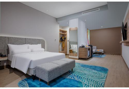 a bedroom with a white bed and a blue rug at Harper Banjarmasin by ASTON in Banjarmasin