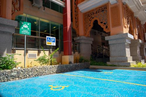 a building with a blue tile floor in front of a building at Paya Bunga Hotel Terengganu in Kuala Terengganu